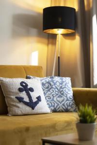 ein Kissen auf einer Couch neben einer Lampe in der Unterkunft Cozy Beachside Falla by Elite Apartments in Zaspa + 6 Fotos