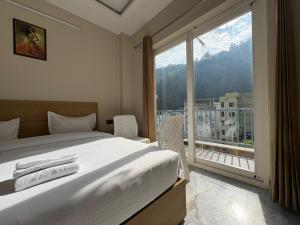 a bedroom with a bed and a large window at Hotel Abline Rishikesh in Rishīkesh