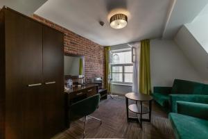 a living room with a green couch and a table at Hotel Artus - Old Town in Gdańsk