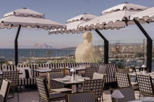 ein Restaurant mit Tischen und Stühlen und einer Statue in der Unterkunft MIM Sotogrande Member of Melia Collection in Sotogrande