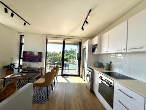 a kitchen with white cabinets and a dining room with a table at Urban Escape - Le Jardin Unit 301 in George