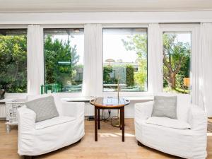 een woonkamer met twee witte stoelen en een tafel bij 8 person holiday home in Ålbæk in Ålbæk