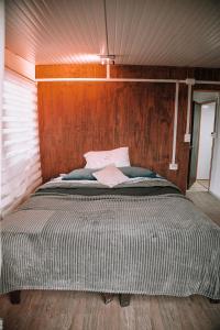 a bed in a room with a wooden wall at Dollinco Lodge in El Cerrillo +10 photos