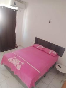 a pink bed with pink sheets and pink pillows at Pousada Apart Praia Uruaú in Beberibe