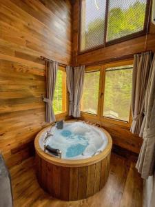 een groot bad in een houten kamer met ramen bij Saffire Doğa Evleri in Güneyköy