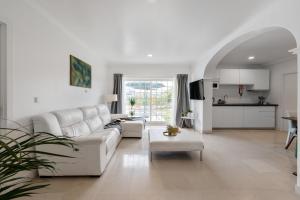 ein weißes Wohnzimmer mit einem weißen Sofa und einem Tisch in der Unterkunft MBird 19 Estoril Apartments in Estoril