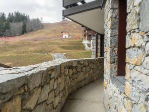 Un muro de piedra al lado de un edificio con vistas. en Bel appartement rénové, 4 pers, balcon, casier à skis - FR-1-291-865, en Valmorel