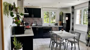 een keuken met zwarte kasten en een tafel en stoelen bij Le Clos de l'Autel 