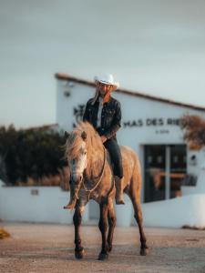 a man riding a horse on a street at Mas des Rièges & Spa in Saintes-Maries-de-la-Mer