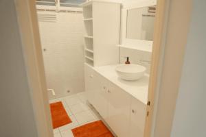 a white bathroom with a sink and a mirror at Bas de villa 3 chambres - Jardin privé - 20 minutes aéroport in Baie-Mahault +15 photos