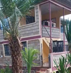 a building with a palm tree in front of it at Sacred Heart Apartments BNB & Hostels Meru Town in Meru