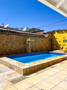 a swimming pool in front of a stone wall at Estrela D Alva Pousada in Pirenópolis