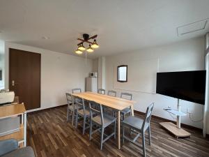 a dining room with a table and chairs and a flat screen tv at とまるん桜山 in Nagoya