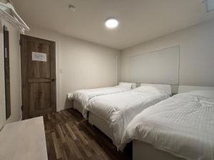 a bedroom with two beds and a door at とまるん桜山 in Nagoya