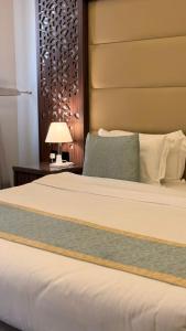 een slaapkamer met een bed en een tafel met een lamp bij Dimond Vision Hotel in Jeddah