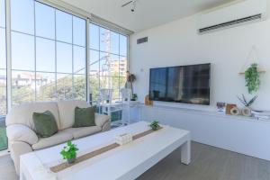 a living room with a white couch and a tv at GlassHaus Rooftop 2-BR W Pool & Terrace in Ghazir in Admā