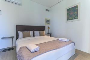 a bedroom with a large bed with two towels on it at GlassHaus Rooftop 2-BR W Pool & Terrace in Ghazir in Admā +24 photos