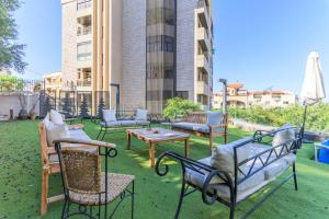 a group of chairs and tables on a lawn at GlassHaus Rooftop 2-BR W Pool & Terrace in Ghazir in Admā