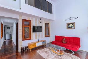 ein Wohnzimmer mit einem roten Sofa und einem Fernseher in der Unterkunft Angkor Nesthouse in Siem Reap