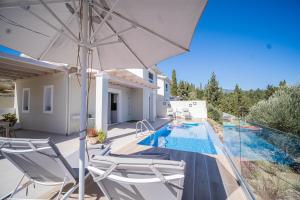 a villa with a swimming pool and an umbrella at Giardinia Holiday Homes with Private Pool in Gazátika