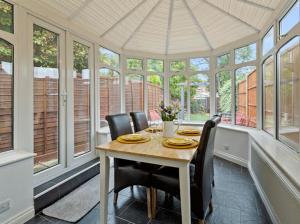 a dining room with a table and chairs and windows at 7 Guests - 6 Bedroom - Free Wi-Fi - NN15 in Burton Latimer