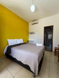 a bedroom with a bed with a yellow wall at Estrela D Alva Pousada in Pirenópolis
