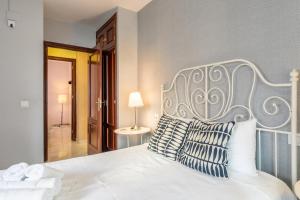 Un dormitorio con una cama blanca con almohadas azules y blancas. en Francos Cathedral, en Sevilla