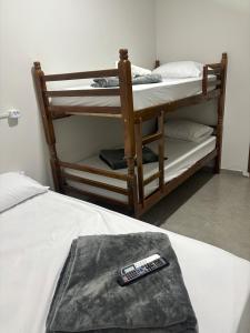 een kamer met 2 stapelbedden en een afstandsbediening bij Apartamento no Centro de Bandeirantes Ar, TV Smart, Ar Condicionado e Frigobar in Bandeirantes
