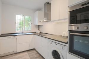 a kitchen with white cabinets and a washer and dryer at Lofty Justa in Seville