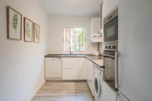 a white kitchen with a sink and a dishwasher at Lofty Justa in Seville +11 photos