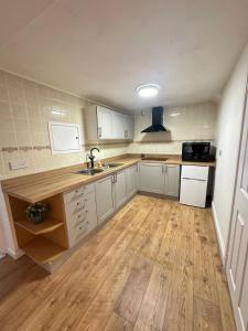 a kitchen with white cabinets and a wooden floor at Spacious apartment in Leigh woods in Bristol