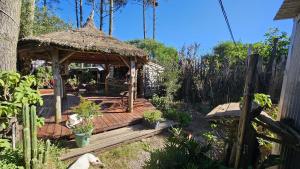 a wooden deck with a gazebo in a garden at Kosmik House in Punta Del Diablo