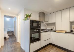 Una cocina con gabinetes blancos y un horno. en Orbyz, en Sevilla