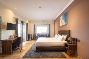 een slaapkamer met een bed, een bureau en een computer bij Nouveau Hotel in Accra