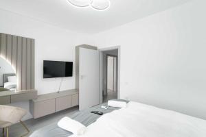 a white bedroom with a bed and a tv at Hori Residence - Confort și Stil în Băile Felix in Cordău