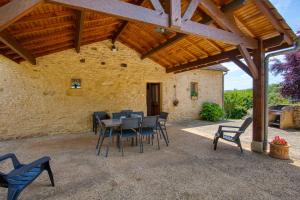 eine Terrasse mit einem Tisch und Stühlen unter einem Holzdach in der Unterkunft GITE LES PIERRES CHAUDES in Veyrignac