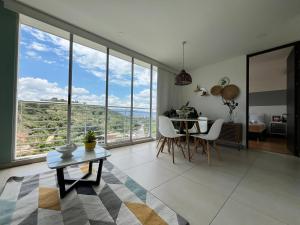 ein Wohnzimmer mit Tisch und Stühlen und großen Fenstern in der Unterkunft Suites con Vista en Floridablanca in Floridablanca