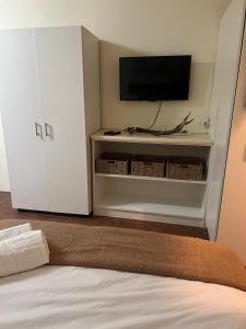 una camera da letto con una TV, un mobile bianco e un letto di Boschberg Accommodation a Somerset East