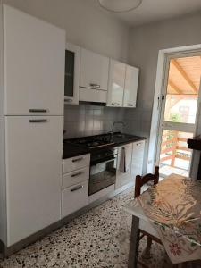 a kitchen with white cabinets and a stove and a table at La Villetta in Vittorito
