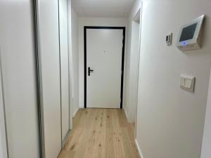 a hallway with a white door and a wooden floor at Bratislava in Nivy