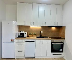 a white kitchen with white cabinets and a microwave at Bratislava in Nivy