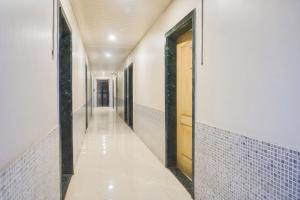 a hallway with white tile walls and a wooden door at Hotel O Atithi Lodge in Wagholi