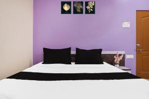 a bedroom with a white bed with a purple wall at Hotel O Atithi Lodge in Wagholi +22 photos