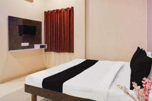 a bedroom with a black and white bed and a tv at Hotel O Atithi Lodge in Wagholi