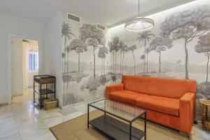 a living room with a orange couch and palm trees mural at San Clemente House in Seville