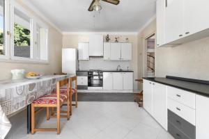 a kitchen with white cabinets and a table and chairs at La Villa Alba by BarbarHouse in Leporano Marina
