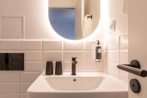 Un baño blanco con lavabo y espejo. en Dantan Hôtel, en Boulogne-Billancourt 31 fotos más