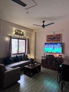Una sala de estar con un sofá y un televisor de pantalla plana. en Homely, Secured, Privacy at Prime Location, en Vadodara