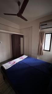 1 dormitorio con 1 cama azul y ventilador de techo en Homely, Secured, Privacy at Prime Location, en Vadodara