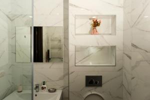 a white bathroom with a toilet and a mirror at HD Didveli Apartment in Bakuriani +15 photos